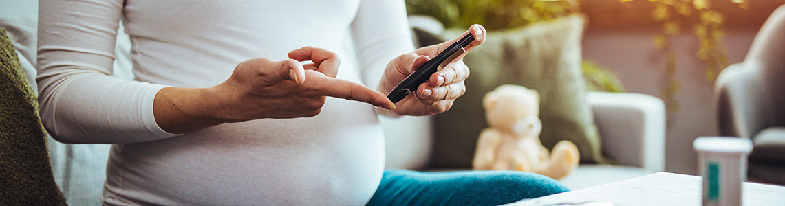A pregnant woman with glucometer checking blood sugar level at home